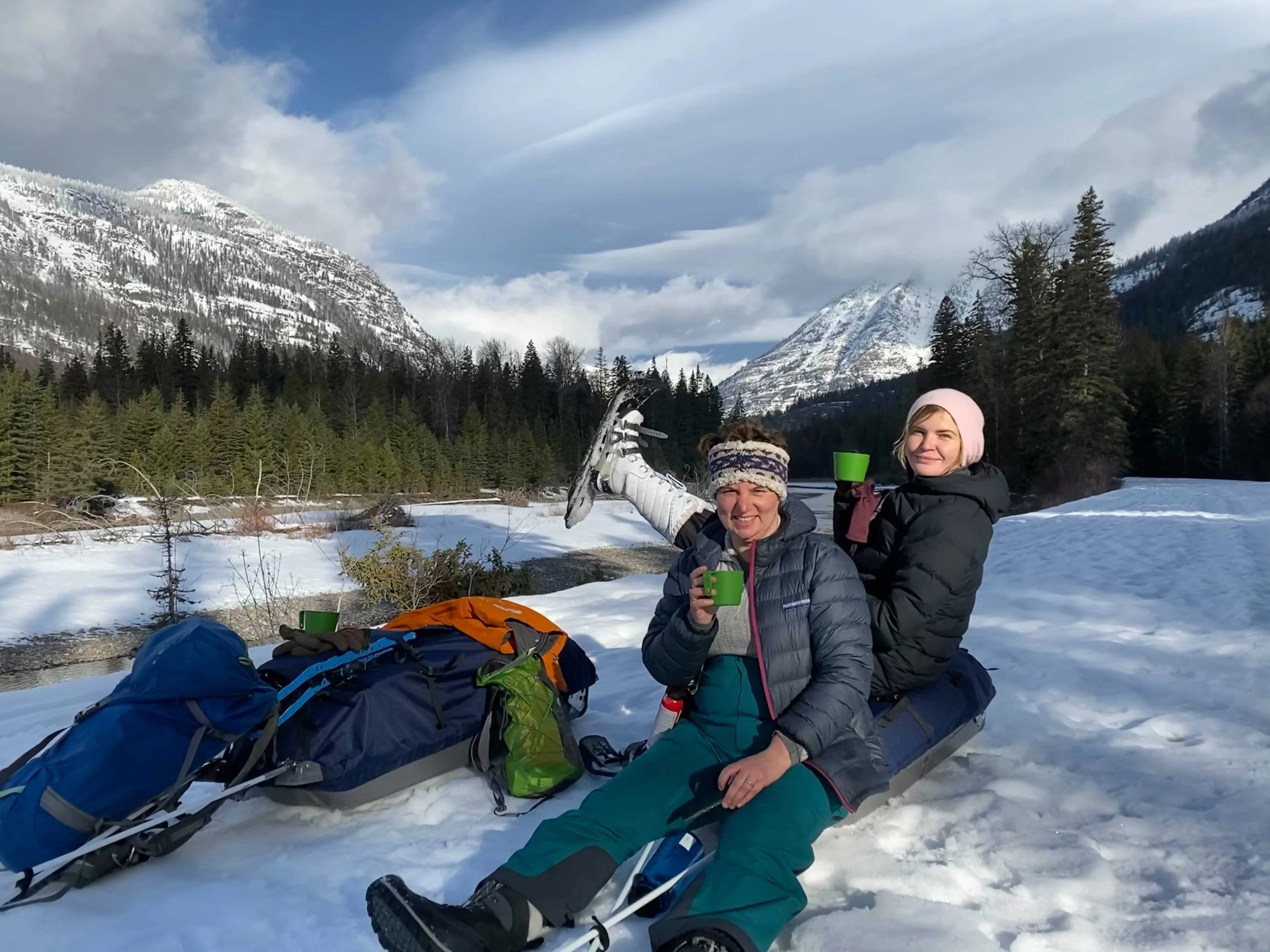 Two people sitting on snow slides